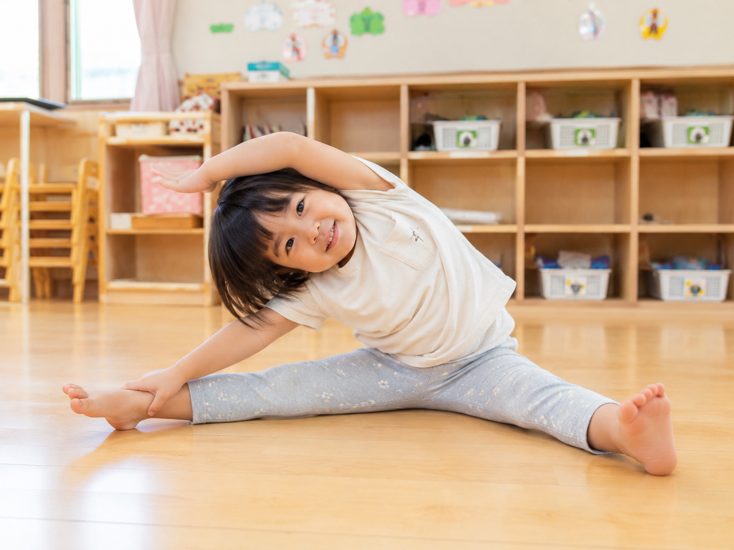 保育室の床でストレッチをする園児